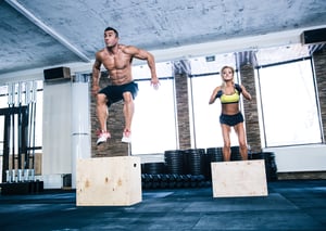 Group of man and woman jumping on fit box at gym