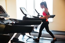 beautiful-young-sportswoman-with-earphones-and-blank-screen-smartphone-using-treadmill-and-drinking-water-in-gym_BKaJICSo.jpg